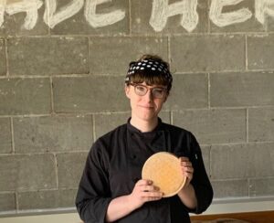 Woman Holds Cheese Wheel