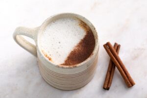 Elderberry Latte Cup Next to Two Cinnamon Sticks