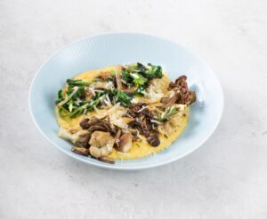 a bowl of creamy polenta with mushrooms and sauteed greens