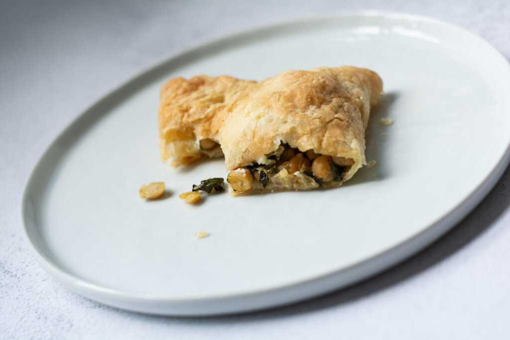 Greek Chickpea Hand Pie Cut in Half on Plate