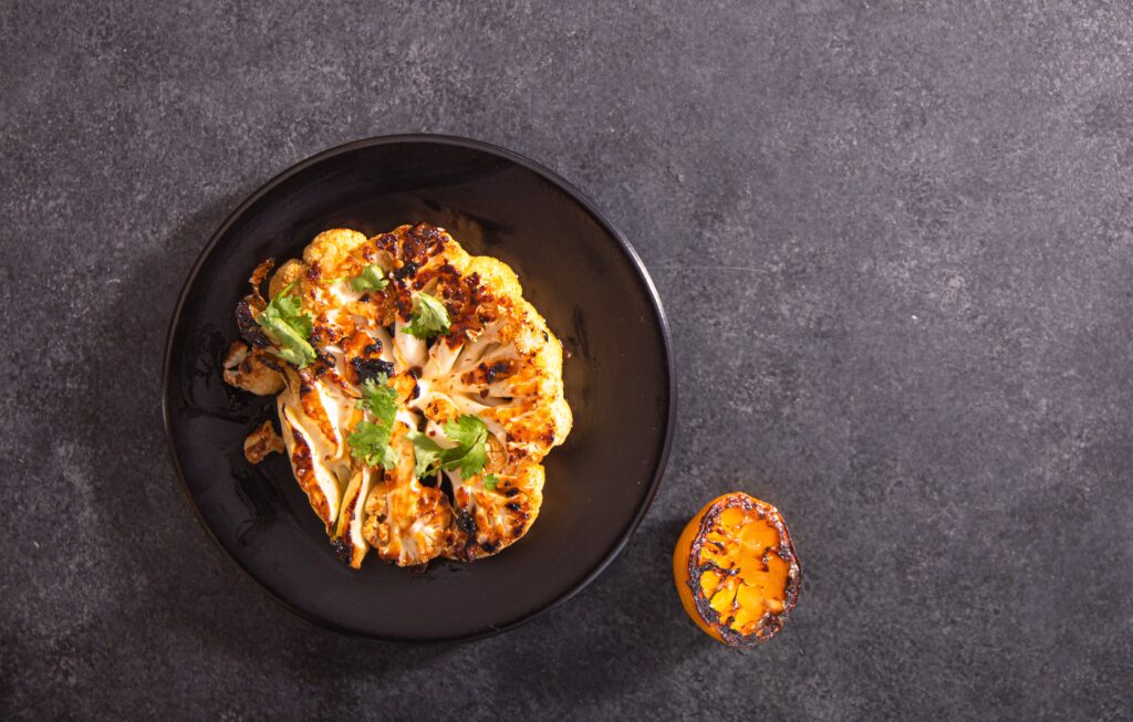 Blackened Cauliflower Steak on a Plate with a Grilled Lemon