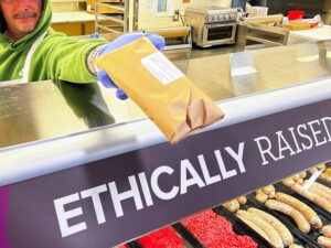 Close up on a package of meat at a service counter being handed toward the camera