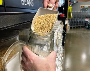 Close up on hands pouring dried grains into a mason jar.