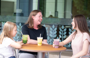 Mom and Two Daughters Enjoying Smoothies at An Outside Table