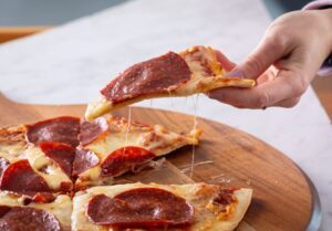 Hand Grabbing a Slice of Pepperoni Pizza