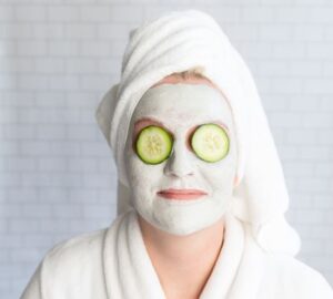 Person with a Face Mask on and Cucumbers on Eyes