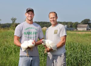 Kadejan Farmers Each Hold a White Chicken in the Field