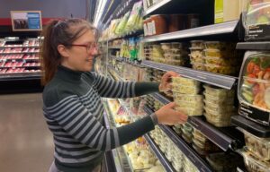 Maya Adding Salads to the Shelf in the Richfield Deli