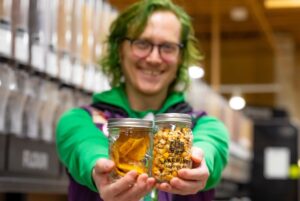 Employee Joker Holds Jars of Dried Mango and Glad Corn