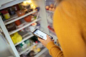 Person Shopping on Phone in Front of Open Fridge