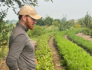 Farmer Tim in Profile Looking at Rows of Vegetables