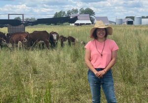 Farmer Wendy in Field with Cattle Grazing Behind Her