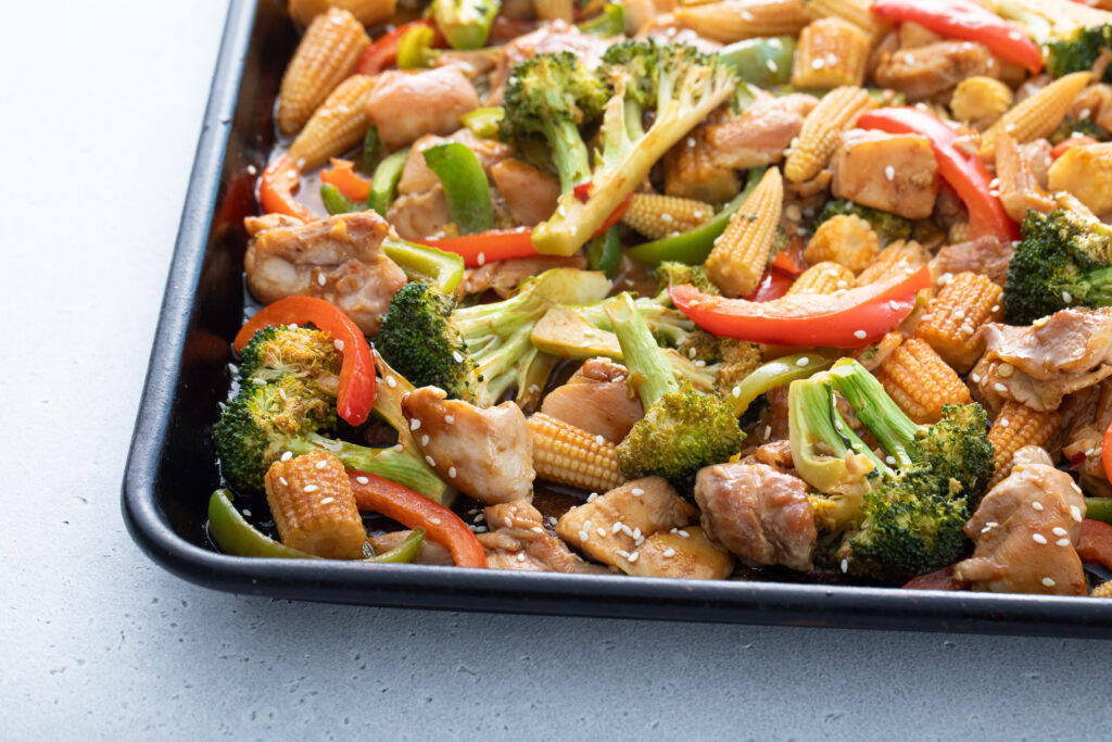 Sheet pan of chicken, broccoli, baby corn, and bell peppers