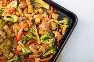 Chicken, broccoli, baby corn, peppers on sheet pan