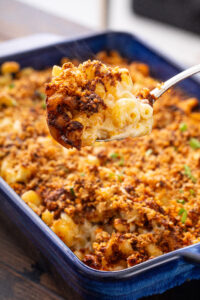 Spoonful of chili crisp mac n cheese from a blue baking dish
