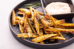 Turnip fries on dark plate with aioli sauce