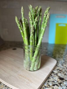 Asparagus in a glass jar on a wooden cutting board