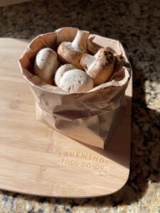 Mushrooms in a paper bag on a wooden cutting board