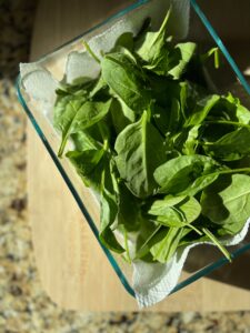 Spinach on a paper towel in a glass container