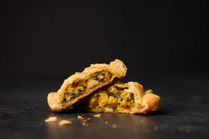 Two Halves of a Chicken Curry Hand Pie on a Black Surface
