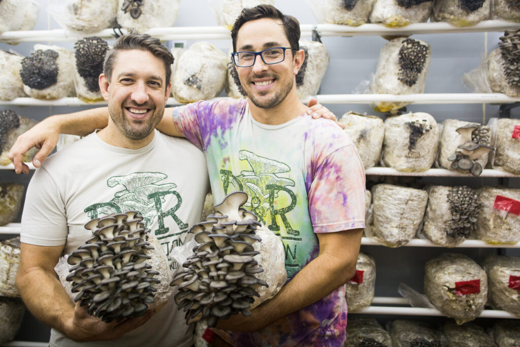 R&R Owners Stand in a Fruiting Chamber Holding Large Mushrooms