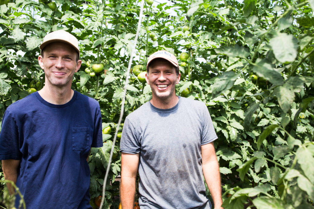 Twin Organics Brothers Stand in Greenhouse